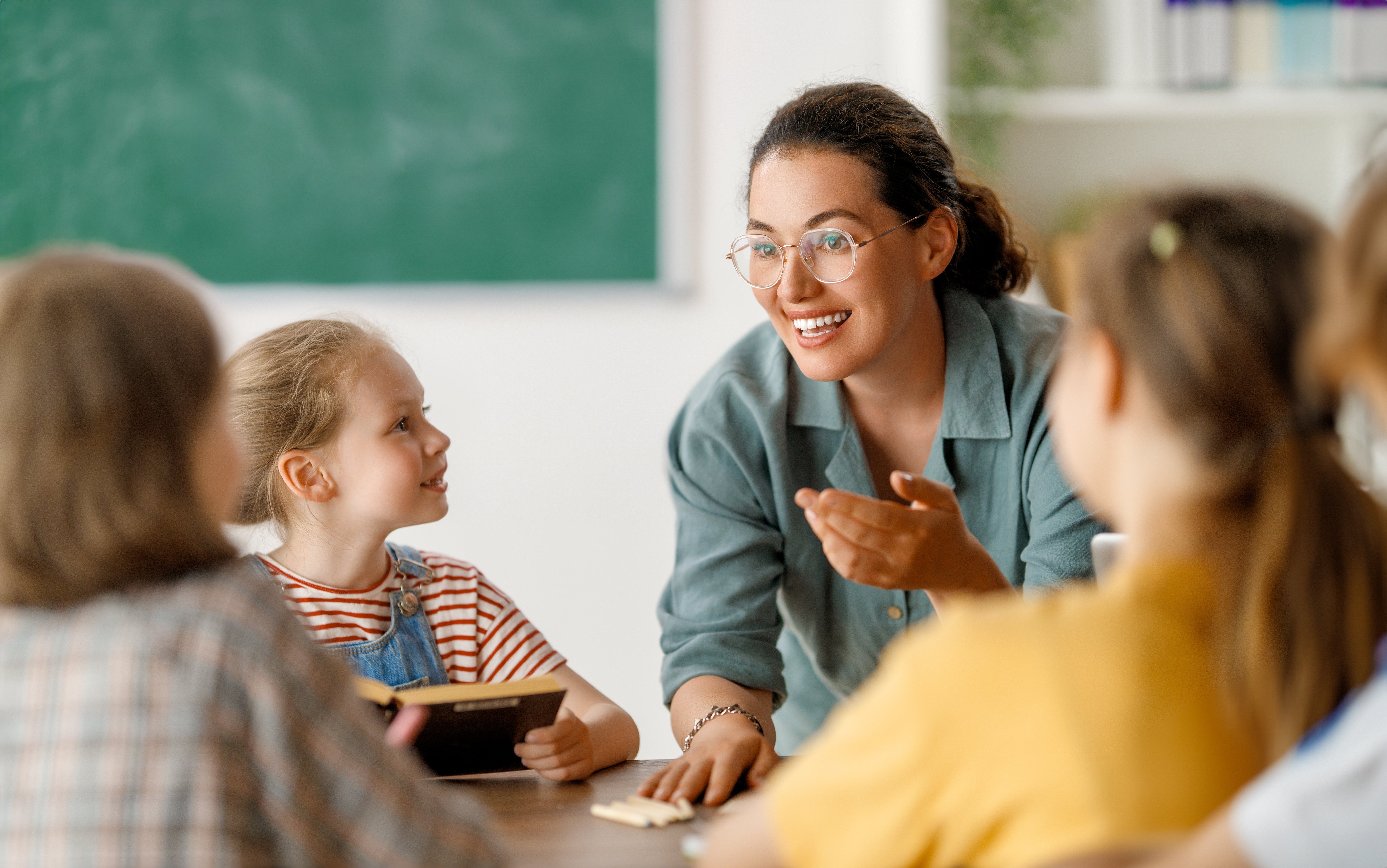 Smiling teacher talking to young children
